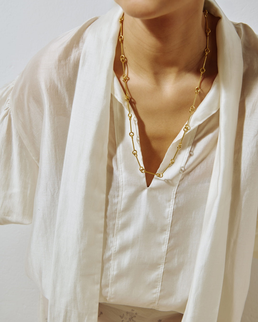 LIL Milan Magnetica gold-plated necklace worn over open white shirt